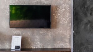 Un téléviseur à écran plat fixé à un mur texturé orné d’un motif décoratif.