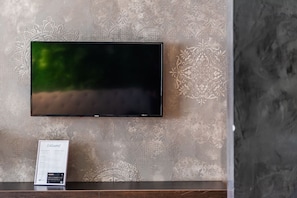 A flat-screen TV mounted on a textured wall with a patterned design. - Vista Mare Horizon Beachfront 1BR Apartment (Orikum)