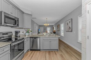 A modern kitchen with stainless steel appliances, a central island, and a view into the living area. - 3652 Claypond Village Ln (Myrtle Beach)