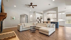 A spacious living room with a sectional sofa, a small round table, and a ceiling fan. - Family Retreat in Creekside • Relax & Unwind (Tomball)
