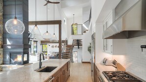 Een moderne keuken met een centraal eiland, een ingebouwde kookplaat en een groot raam met uitzicht op een balkon.