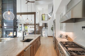 Una cocina moderna con una isla central, estufa integrada y un amplio ventanal con vistas a un balcón.