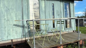 A rustic wooden building with a porch, a metal railing, and a small table.