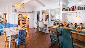 A spacious dining area with a high ceiling, hexagonal floor tiles, and a bar area with various bottles and a vintage television. - Amazing 5-bedroom farmhouse in quaint Rolling Hills Estates with AC and nature! (Rolling Hills Estates)