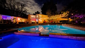 A swimming pool with a reflection, surrounded by a building with multiple windows and a balcony. - Amazing 5-bedroom farmhouse in quaint Rolling Hills Estates with AC and nature! (Rolling Hills Estates)