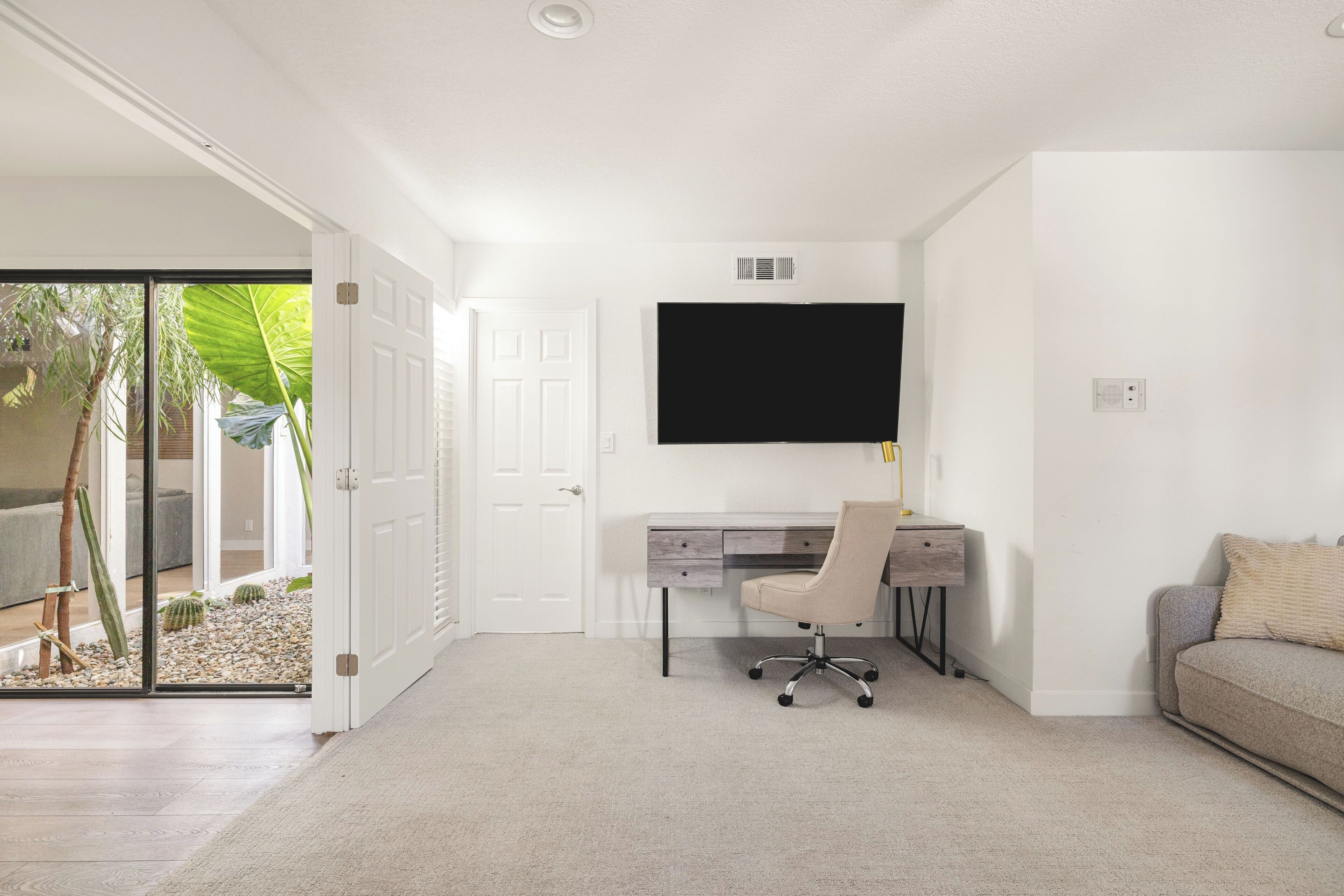 A modern room with a desk, chair, and a flat-screen TV mounted on the wall.