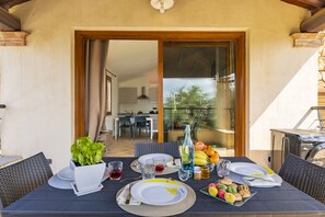 An outdoor dining area with a table set for two, including plates, cutlery, glasses, and a variety of food items. - Mary's Vacation Home Near the Ocean (Tortoli')