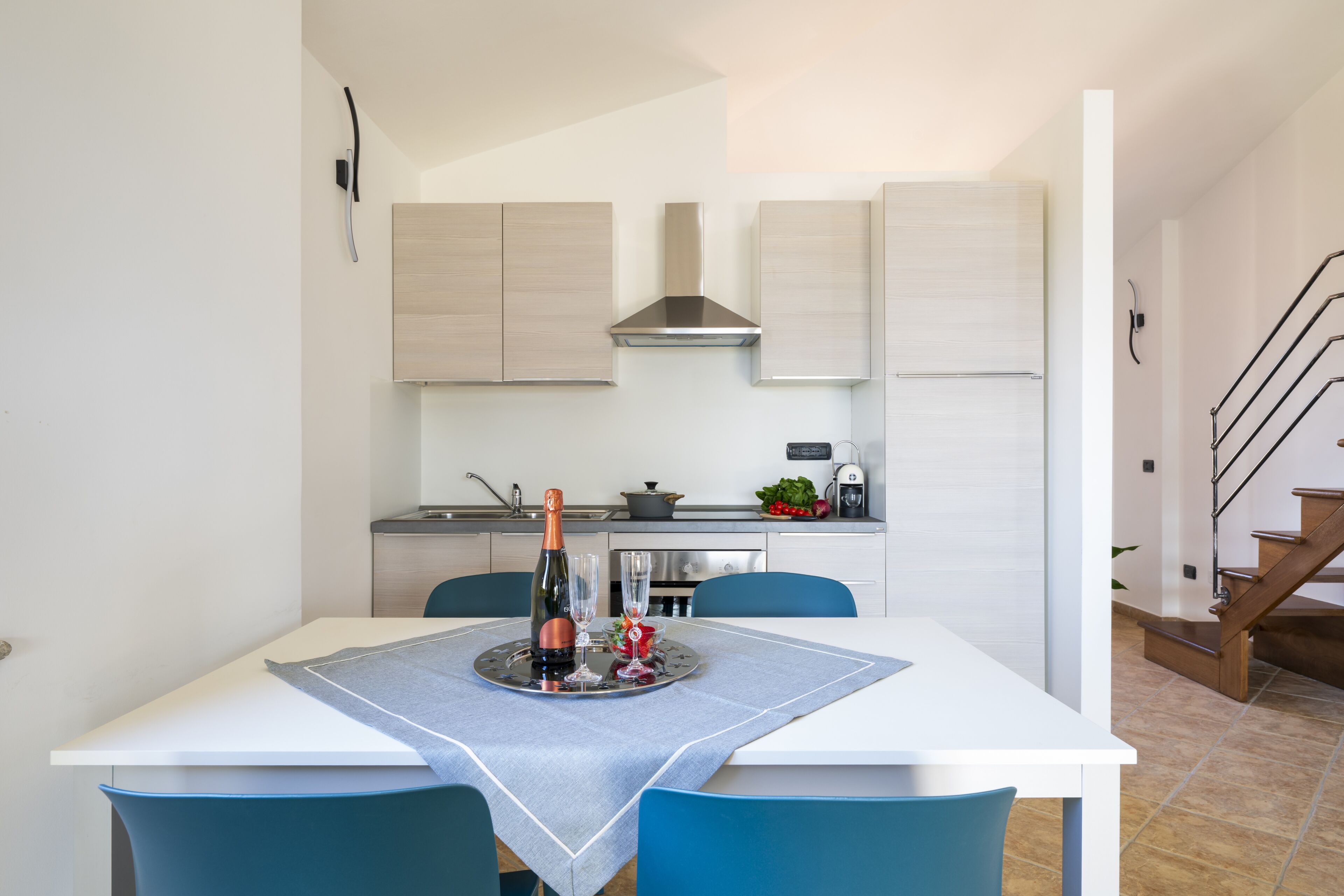 Een moderne keuken met witte kasten, een roestvrijstalen afzuigkap en een eethoek met een tafel voor twee personen.