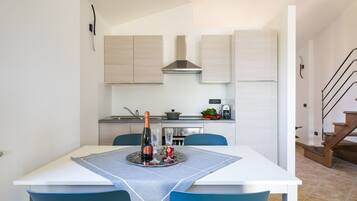 Een moderne keuken met witte kasten, een roestvrijstalen afzuigkap en een eethoek met een tafel voor twee personen.