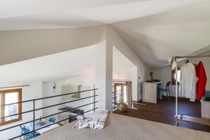 Une chambre spacieuse de style loft, dotée d’une grande fenêtre, d’un balcon, d’un coin cuisine et d’un bureau.