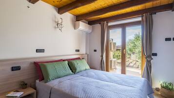 Een slaapkamer met een bed, nachtkastje, een wandairconditioner en uitzicht op buiten.