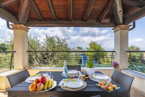 An outdoor dining area with a table set for two, a bottle of water, and a variety of fruits and pastries. - Mary's Vacation Home Near the Ocean (Tortoli')