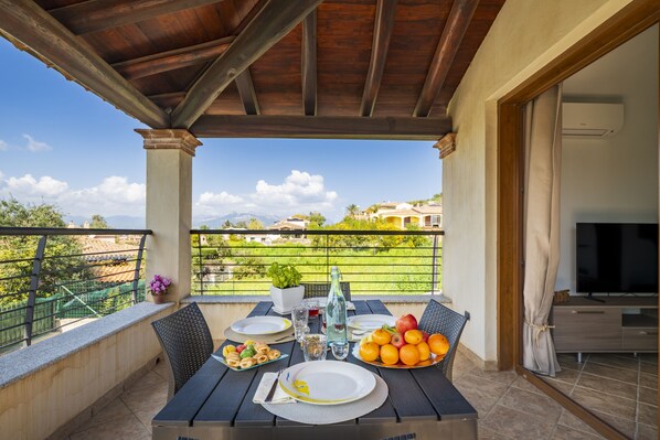 Un balcon avec une table dressée pour les repas, un téléviseur et une vue sur le paysage.