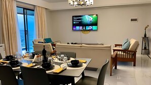 A modern dining area with a table set for two, a sofa, and a television mounted on the wall. - Luxury 6-Bed Penthouse with Sky Terrace (Nairobi)
