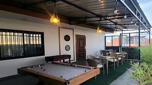 A pool table with billiard balls, a dartboard, and a door leading to a seating area with tables and chairs. - Luxury 6-Bed Penthouse with Sky Terrace (Nairobi)
