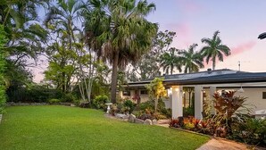 Ein Haus mit gepflegtem Rasen, Palmen und einem Garten mit verschiedenen Pflanzen.