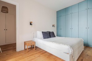 A bedroom with a bed, a nightstand, a wardrobe, and two wall-mounted light fixtures. - Blueground | Europe, elevator, nr Parc Monceau (Paris)