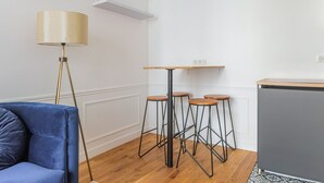 Ein gemütlicher Wohnbereich mit Sofa, Stehlampe, einem kleinen Tisch mit Hocker und einem Schrank.