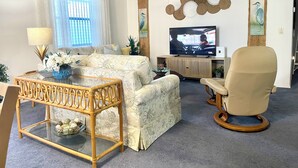 Uma sala de estar com sofá, mesa de centro, televisão e arte decorativa na parede.