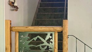 A staircase with a wooden handrail and a decorative glass panel featuring a mountain and deer. - Peaceful Shaver Lake Mountain Retreat with Deck & Forest Views (Shaver Lake)