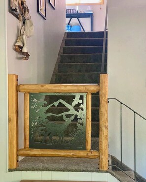 Eine Treppe mit einer Holzhandläufe und einem dekorativen Glasfenster mit einer Berg- und Hirschdarstellung.