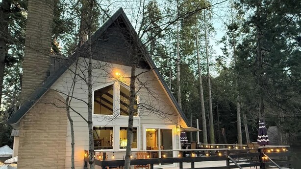 A cabin with a deck, surrounded by trees, and a dock extending into a body of water. - Peaceful Shaver Lake Mountain Retreat with Deck & Forest Views (Shaver Lake)