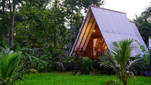 A triangular-shaped building with a sloped roof, surrounded by lush greenery and trees.