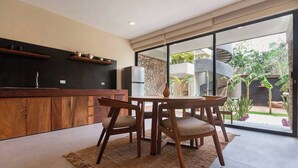 A modern kitchen with a dining area, wooden furniture, and a view of the garden. - Modern 1-bedroom studio with Sunken Pool, AC and gym access in La Veleta, Tulum (Tulum)