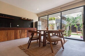 A modern kitchen with a dining area, wooden furniture, and a view of the garden. - Modern 1-bedroom studio with Sunken Pool, AC and gym access in La Veleta, Tulum (Tulum)