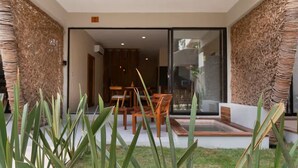 A modern interior with a dining area, a glass door leading to an outdoor space, and a small garden area with plants. - Modern 1-bedroom studio with Sunken Pool, AC and gym access in La Veleta, Tulum (Tulum)
