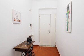 Ein Zimmer mit einer Nähmaschine auf einem Tisch, einer weißen Tür und zwei gerahmten Bildern an den Wänden.