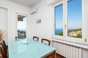 A dining area with a glass table, chairs, and a view of the sea through large windows. - Panoramic Sea-View Terrace in the Quiet Beauty of the Sorrento Coast (Massa Lubrense)