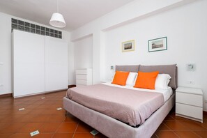 Ein Schlafzimmer mit einem Bett, Nachttischen, einem Kleiderschrank und zwei gerahmten Bildern an der Wand.