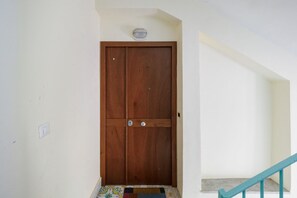 A wooden double door with a light switch and a small light fixture above it. - Panoramic Sea-View Terrace in the Quiet Beauty of the Sorrento Coast (Massa Lubrense)