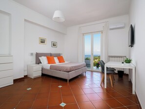 Une chambre à coucher comprenant un lit, un bureau, une chaise, une fenêtre avec vue et un appareil de climatisation.