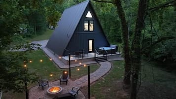 A triangular-shaped cabin with a deck, surrounded by trees.