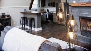 A loft-style living space with exposed wooden beams, a kitchen area, and a fireplace.