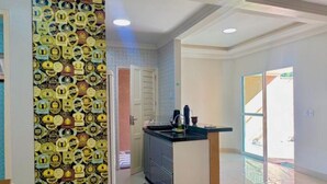 A modern kitchen with a central island, a dining area with a table and chair, and a patterned wall.