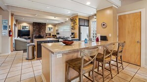 Una cucina moderna con isola centrale, sgabelli da bar e una parete a contrasto in pietra.
