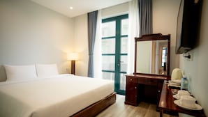 Una camera d'albergo con un letto, una cassettiera, uno specchio e una televisione.