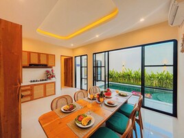Una cocina moderna con comedor, ventanas amplias y vista a una piscina.