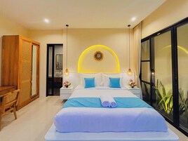 Habitación de hotel con cama, mesitas de noche, espejo, armario y un ventanal grande.