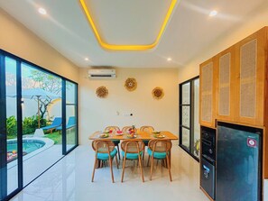 Uma área de refeições com mesa, cadeiras e um frigorífico.