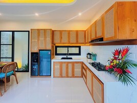 Una cocina moderna con armarios de madera, microondas integrado, refrigerador y estufa a gas.