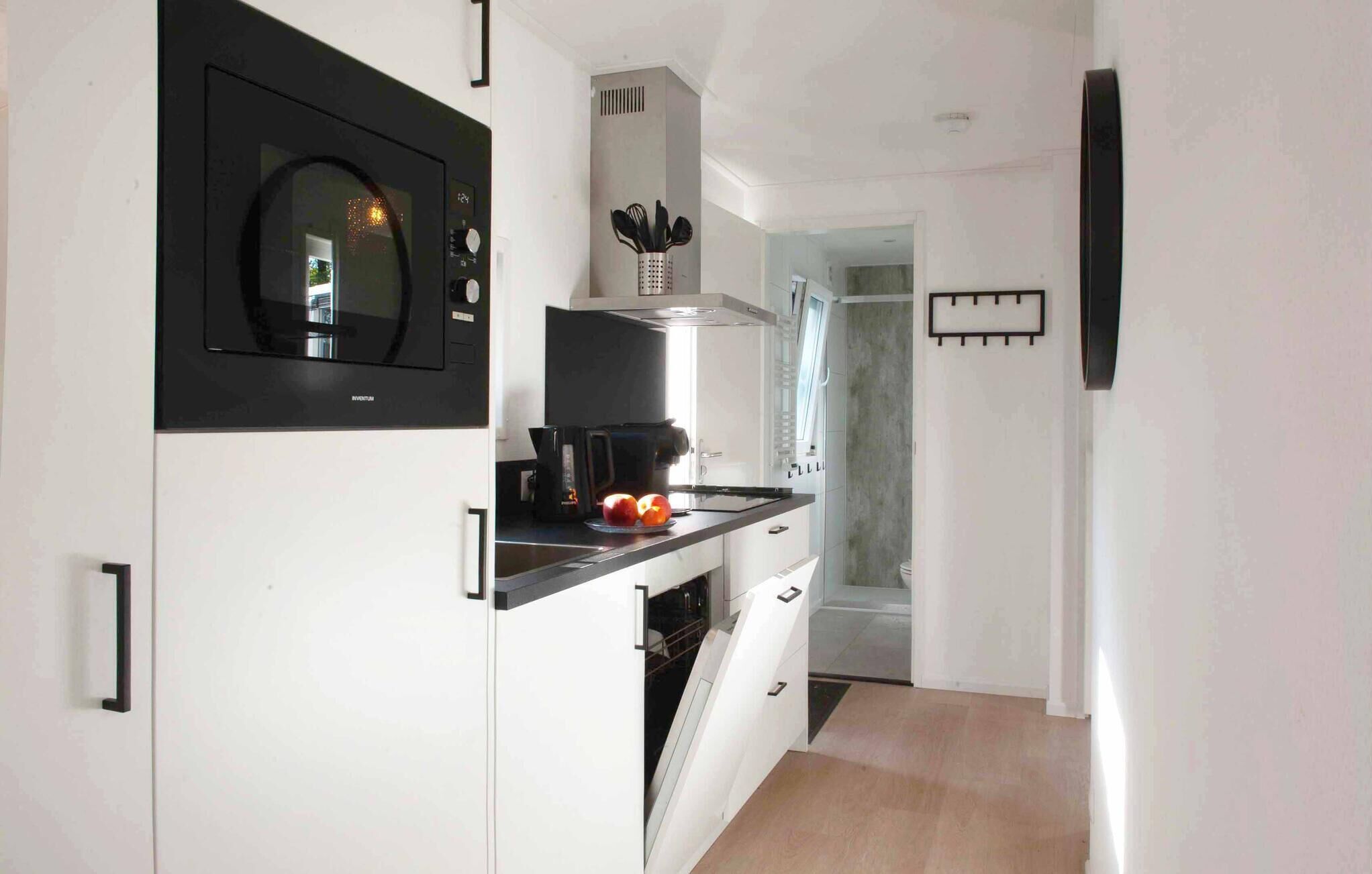 A modern kitchen with a microwave, coffee maker, and a window.