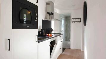A modern kitchen with a microwave, coffee maker, and a window.