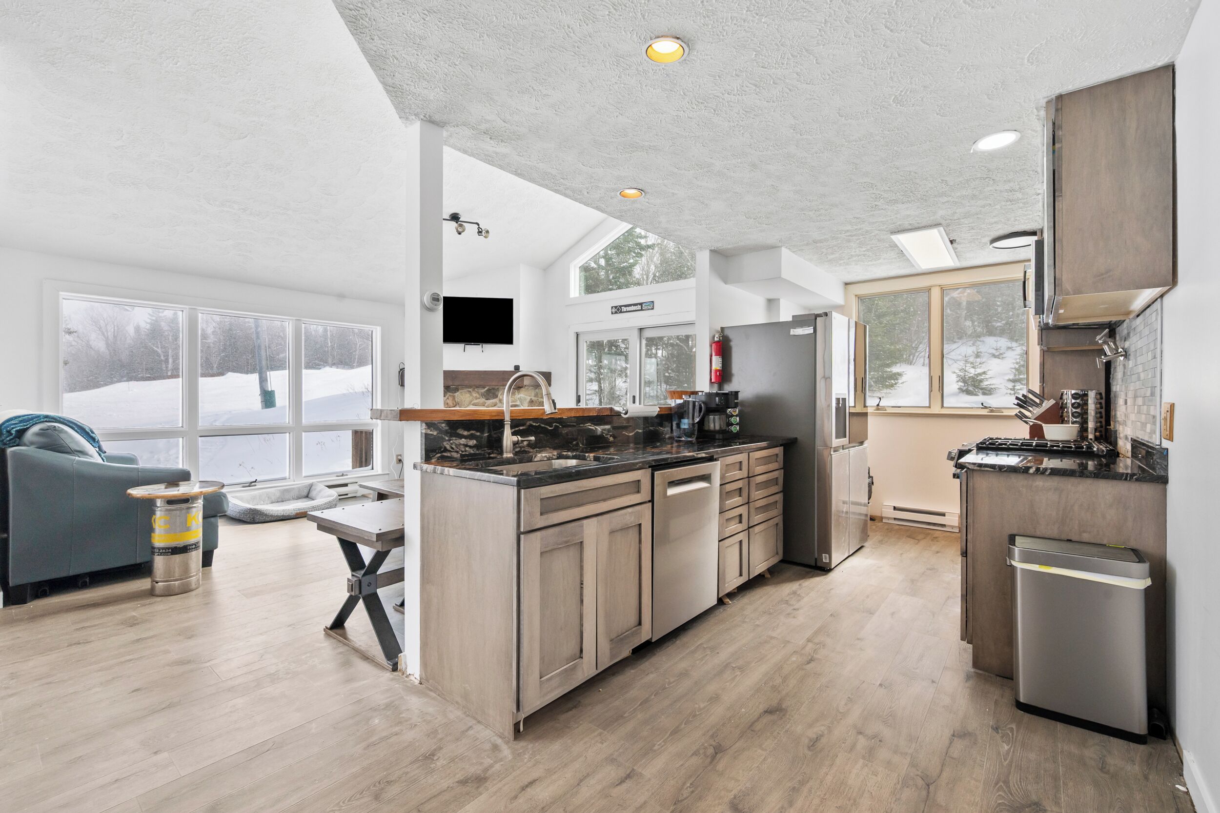 Une cuisine moderne dotée d’un îlot central, de meubles en bois et d’une grande fenêtre.