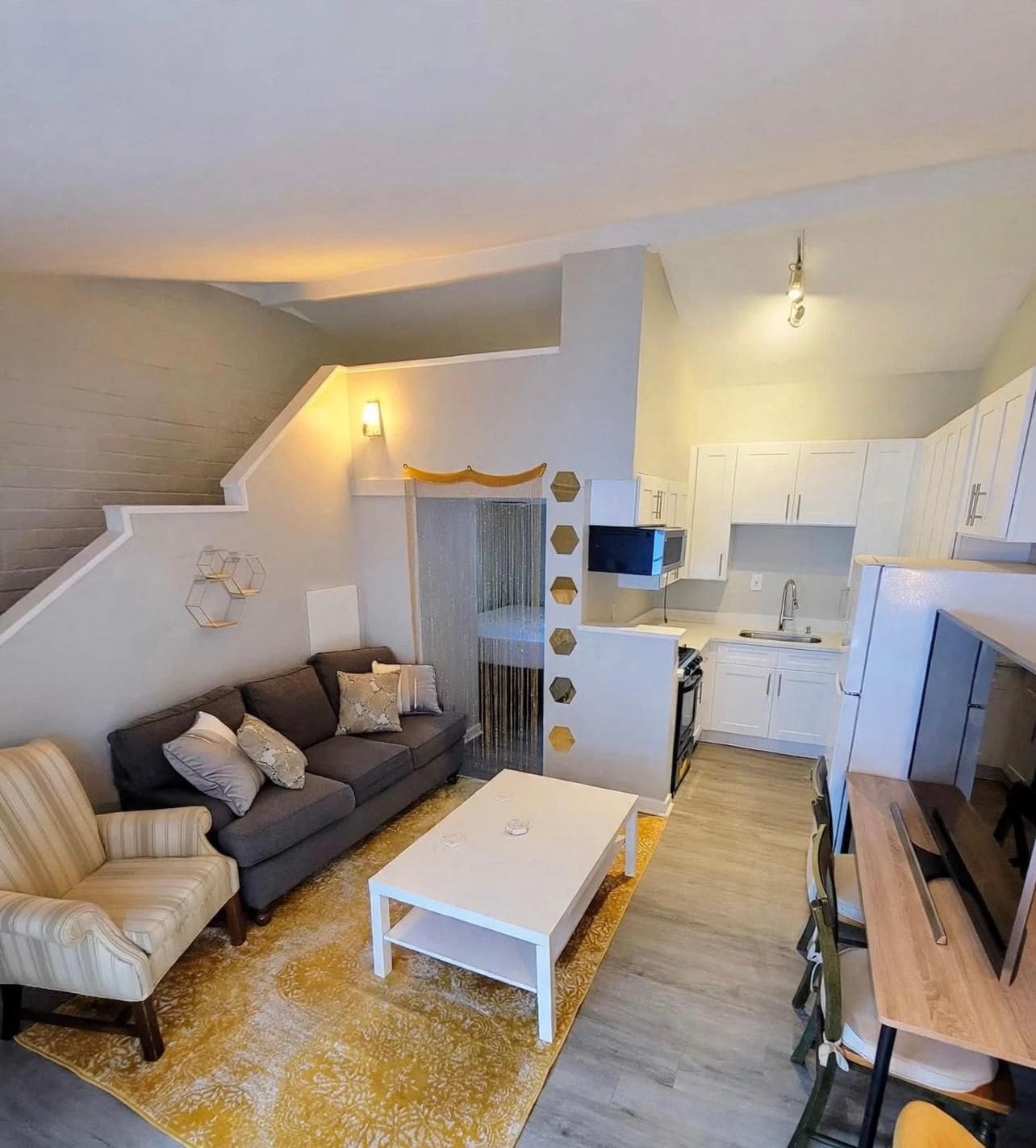 A modern apartment with a living area, a kitchen, and a staircase.