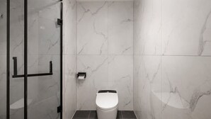 A bathroom with a toilet, a glass shower enclosure, and marble walls. - Chengdu Suli Travel Hotel (Chengdu)