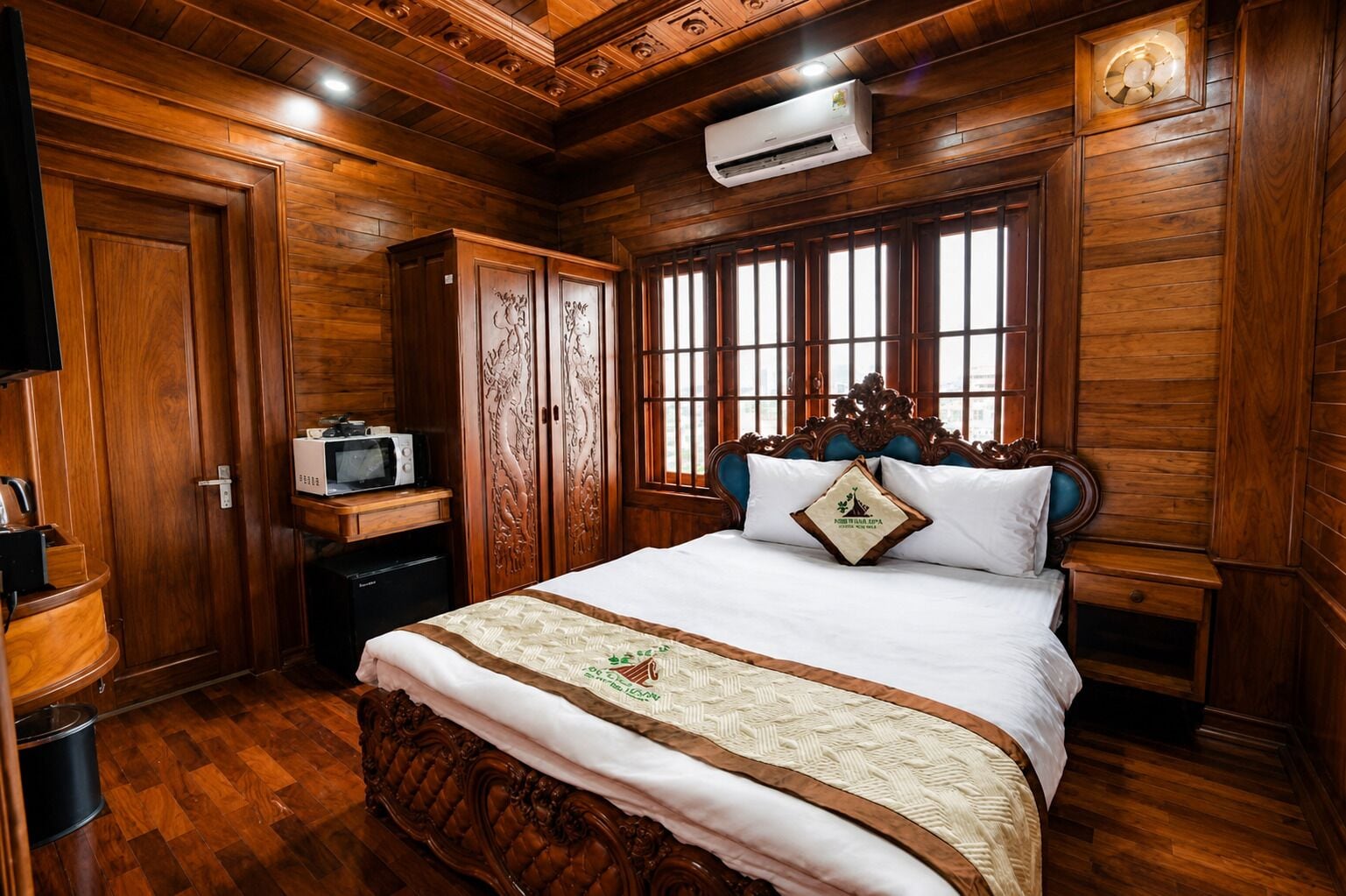 A wooden room with a bed, wardrobe, and a microwave.